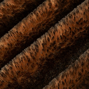 May include: Close-up of a brown and orange faux fur fabric with a striped pattern. The fabric has a soft, plush texture.