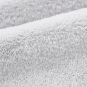 May include: Close-up of a soft, white, fluffy fabric with a fuzzy texture.