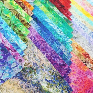 May include: A collection of fabric swatches in a variety of colors, including blue, green, purple, and red. Each swatch has a unique, marbled pattern. The edges of the fabric are cut with a zig-zag pattern.