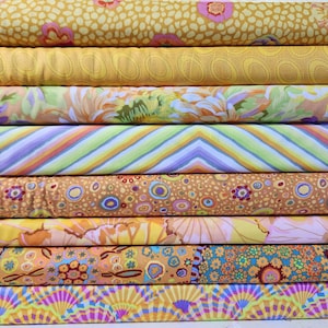 Könnte beinhalten: Eine Auswahl an Stoffrollen mit verschiedenen Mustern. Die Stoffe zeigen florale, gestreifte und gepunktete Designs in Gelb-, Orange-, Grün- und Lilatönen. Ideal für Nähen, Quilten und andere Bastelprojekte, die eine Vielzahl von Textiloptionen bieten.