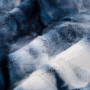May include: Close-up of a soft, blue and white faux fur throw blanket. The fabric has a fluffy, plush texture.