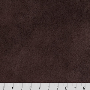 May include: A close-up of a dark brown faux fur fabric. The fabric has a soft, plush texture.