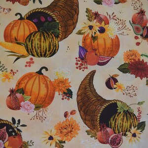 May include: A fabric pattern featuring autumn harvest elements. The design includes orange pumpkins, gourds, cornucopias, pomegranates, figs, and sunflowers. The color palette is warm, with shades of orange, brown, and yellow on a cream background.