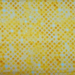 May include: A yellow fabric featuring a repeating pattern of solid orange circles arranged in a grid. The background consists of a mottled yellow texture with small, scattered white dots interspersed between the larger orange circles.