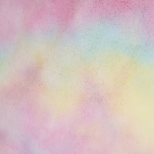 Op de afbeelding: Een zachte, pluche stof met een tie-dye patroon in tinten roze, geel, blauw en groen.