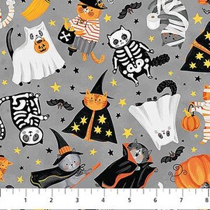 Puede incluir: Tela con temática de Halloween con gatos de dibujos animados disfrazados. Los gatos están vestidos de fantasmas, esqueletos, brujas y momias, sobre un fondo gris con estrellas y murciélagos. Una regla es visible en la parte inferior de la tela.