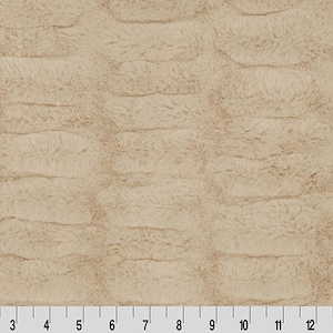 Puede incluir: Primer plano de una tela de piel sintética beige con un patrón texturizado y acanalado. La tela tiene un aspecto suave y afelpado. Una regla está en la parte inferior, mostrando las medidas en centímetros.