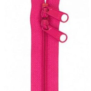 Könnte beinhalten: Ein leuchtend pinkfarbener Reißverschluss mit zwei Metall-Schiebern. Der Reißverschluss ist geschlossen und bereit, in ein Kleidungsstück oder ein Projekt eingenäht zu werden.