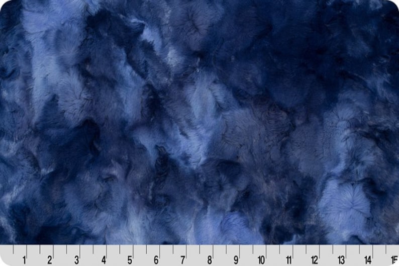 Op de afbeelding: Een close-up van een blauwe nep bont stof met een marmerpatroon. De stof heeft een zachte, pluche textuur.