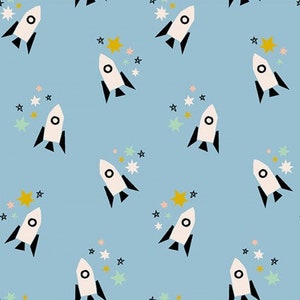 May include: A seamless pattern featuring white rockets with black accents on a light blue background. The rockets are surrounded by colorful stars.