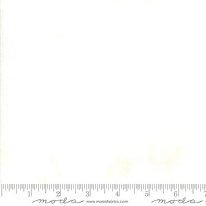 May include: A white fabric with a subtle texture. The fabric is marked with a ruler in inches and the word "moda" appears twice on the bottom edge.