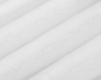 Peut inclure: Tissu en fausse fourrure blanc avec une texture douce et moelleuse. Le tissu est disposé en lignes diagonales, créant un motif subtil.