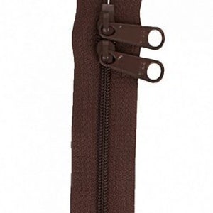 May include: A brown zipper with two pull tabs. The zipper is closed and ready to be sewn into a garment.