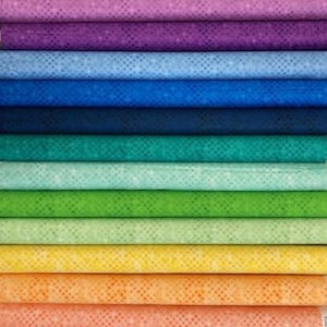 May include: A stack of folded fabric bolts arranged in a gradient of colors including cream, pink, purple, blue, teal, green, yellow, orange, and red. Each fabric features a subtle, repeating geometric dot pattern across the entire surface.