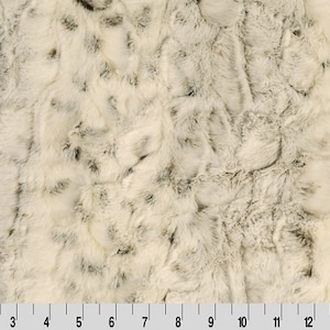 May include: White and gray faux fur fabric with a soft, fluffy texture. The fabric has a subtle pattern of swirls and streaks.