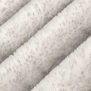 May include: Close-up of a soft, white, and gray plush fabric. The material has a textured, fur-like appearance with diagonal ridges. The fabric appears to be a blanket or throw, offering a cozy and inviting aesthetic.