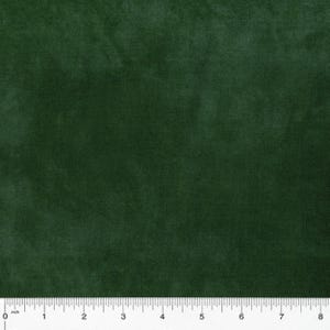 May include: Close-up of a dark green fabric with a soft, velvety texture. The fabric appears to be a solid color, with subtle variations in tone. The image includes a ruler along the bottom edge, showing inch measurements.