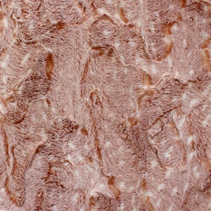 Puede incluir: Primer plano de una tela suave y peluda con un patrón de color marrón y blanco. La tela tiene una textura peluda, que se asemeja a la piel sintética.