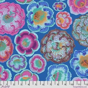 May include: A blue fabric featuring a repeating pattern of multi-colored flowers in shades of pink, purple, teal, and orange. A white ruler at the bottom shows measurements in inches, indicating the scale of the floral print on the textile.