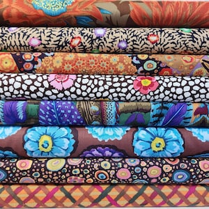 May include: A stack of eight fabric rolls featuring a variety of colourful patterns, including floral, geometric and abstract designs. The fabrics are arranged vertically, with the top roll being a brown fabric with a floral pattern.