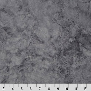May include: A close-up of a gray faux fur fabric with a marbled pattern. The fabric has a soft, plush texture.