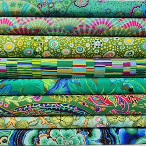 May include: A stack of eight fabric rolls with various green, blue, pink, and purple patterns. The fabrics feature geometric, floral, and abstract designs.