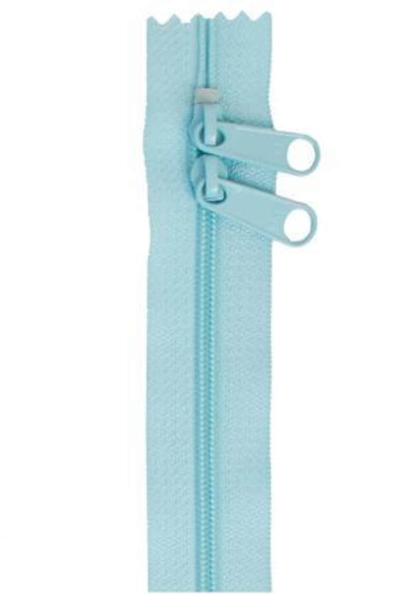 May include: A light blue zipper with two pull tabs. The zipper is closed and has a smooth finish.