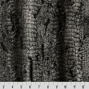 May include: Black and white faux fur fabric with a textured, shaggy look. The fabric has a vertical striped pattern.