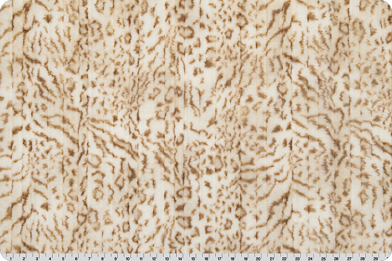 Pu&ograve; includere: Tessuto bianco con un motivo a stampa animale marrone. Il tessuto ha una texture morbida e soffice.