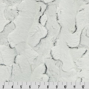 Puede incluir: Tela de piel sintética blanca con un patrón de remolino. La tela tiene una textura suave y mullida.