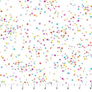 May include: White fabric with a scattered pattern of colorful confetti shapes, including stars, circles, triangles, and rectangles. The confetti is in shades of red, orange, yellow, green, blue, and purple. A ruler is at the bottom of the image.