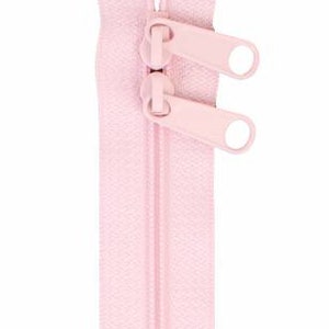May include: A pink zipper with two pull tabs. The zipper is closed and ready to be sewn into a garment.