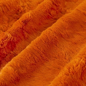 May include: Close-up of a soft, orange faux fur fabric. The fabric has a plush texture and a subtle sheen.