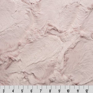 May include: A soft, plush fabric in a light pink colour. The fabric has a fluffy, fuzzy texture.