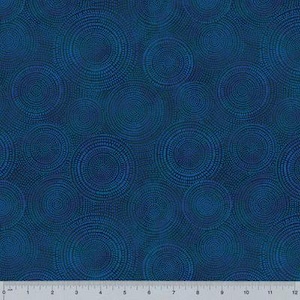 May include: A dark blue fabric featuring a repeating pattern of concentric circles created by small dots. A white ruler is visible at the bottom edge, showing a scale of 12 inches, indicating the scale of the circular dot design on the textile.