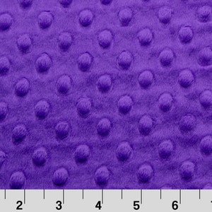 May include: Purple minky fabric with a textured dot pattern. The fabric is soft and plush, making it ideal for blankets, pillows, and other crafts.