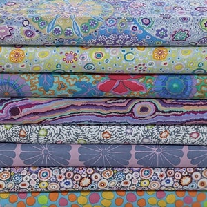 May include: A collection of patterned fabrics in a stack. The fabrics display a variety of floral and abstract designs in shades of blue, purple, green, and orange. The patterns include flowers, circles, and organic shapes, creating a vibrant and artistic display.