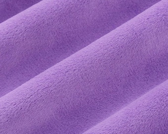 Peut inclure: Gros plan sur un tissu doux et pelucheux de couleur violet clair. Le tissu a une texture duveteuse et un léger brillant.