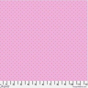 Op de afbeelding: Een roze stof met een herhalend patroon van kleine, donkergrijze stippen. Een liniaal langs de onderrand is gemarkeerd in inches, equivalent aan centimeters.