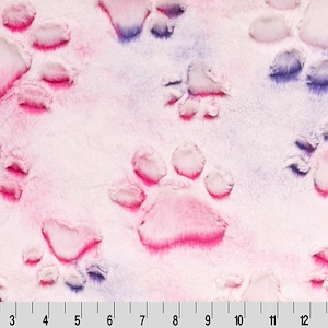 May include: A plush fabric featuring a repeating pattern of paw prints in shades of pink, purple, and white. The paw prints are raised, giving a textured appearance. The fabric is soft and fluffy, with a gradient effect.
