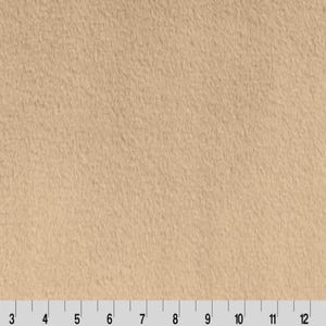 May include: A close-up of a beige, fuzzy fabric. The fabric has a soft, plush texture.