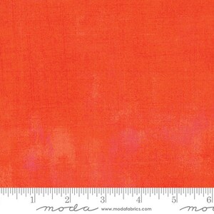 May include: A solid orange fabric with a subtle textured pattern. The fabric is measured with a ruler that reads "moda" and "www.modafabrics.com".