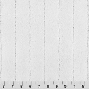 Puede incluir: Tela blanca con un patrón texturizado vertical. El patrón consiste en rayas irregulares en relieve que recorren la longitud de la tela. Una regla en la parte inferior muestra las medidas en pulgadas.