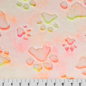May include: A white fabric with a pink, orange, and yellow tie-dye pattern. The fabric has a raised texture of paw prints.