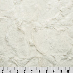 May include: White faux fur fabric with a soft, fluffy texture. The fabric has a swirling pattern and is ideal for crafting projects.