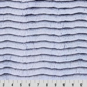 Puede incluir: Primer plano de una tela suave y peluda con un patrón ondulado a rayas en tonos de azul claro y blanco.