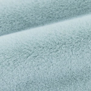 May include: Close-up of a soft, light blue faux fur fabric. The fabric has a plush, velvety texture.