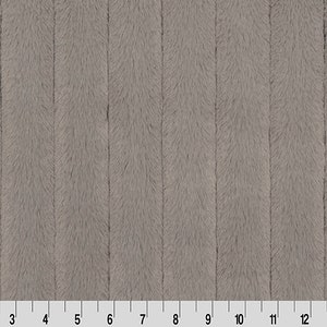 Puede incluir: Primer plano de una tela gris y afelpada con un diseño de costillas verticales. La tela tiene una textura suave y peluda, y una regla es visible en el borde inferior, con medidas en centímetros.