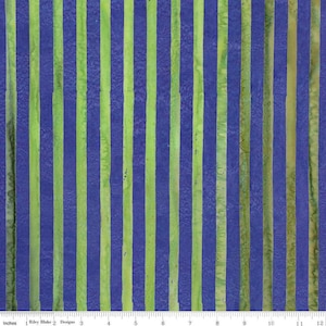 May include: Fabric with vertical stripes in shades of blue and green. The stripes are uneven in width and have a watercolor-like effect. The fabric is marked with inches along the bottom edge. The text "Riley Blake Designs" is visible.