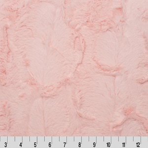 May include: A close-up of a soft, pink faux fur fabric with a fluffy texture. The fabric has a subtle swirl pattern.